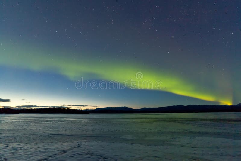 Northern Lights and morning dawn over frozen lake