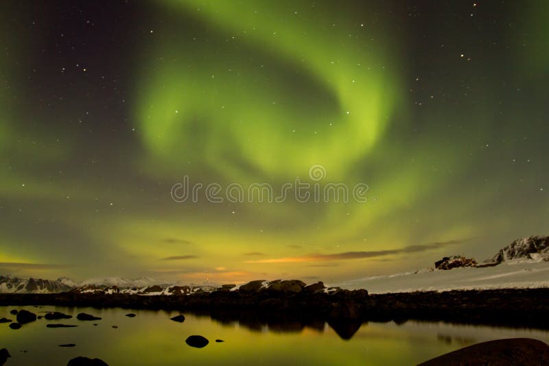 Aurora borealis (Northern lights) view from Lofoten (Norway) with mountains in the distance and reflection in quiet water. Aurora borealis (Northern lights) view from Lofoten (Norway) with mountains in the distance and reflection in quiet water.