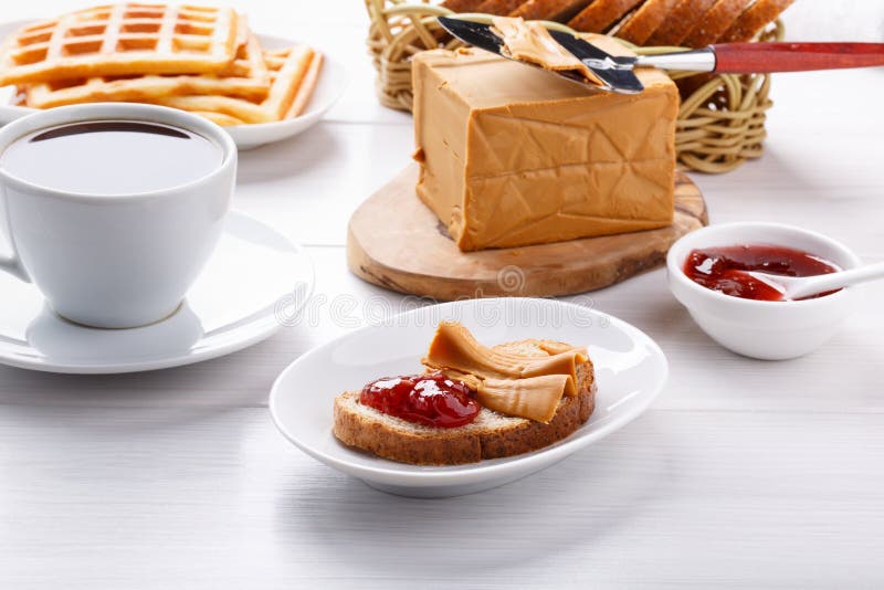Norwegian brunost on white table. Breakfast with Scandinavian brown cheese, bread and coffee stock images Norwegian brunost on white table. Breakfast with Scandinavian brown cheese, bread and coffee stock images