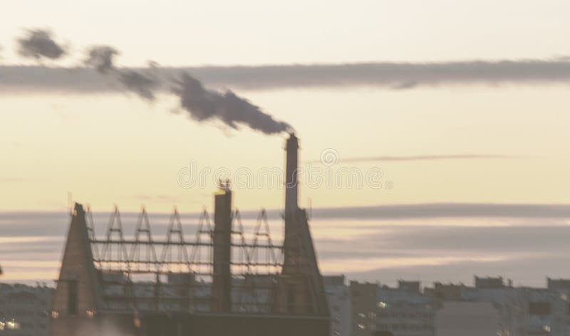 Not a sharp abstract background. Not sharp blurred cityscape. City silhouette with a smoking industrial chimney against the sky at royalty free stock photography