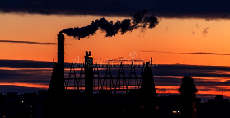 Not a sharp abstract background. Not sharp blurred cityscape. City silhouette with a smoking industrial chimney against the sky at stock images