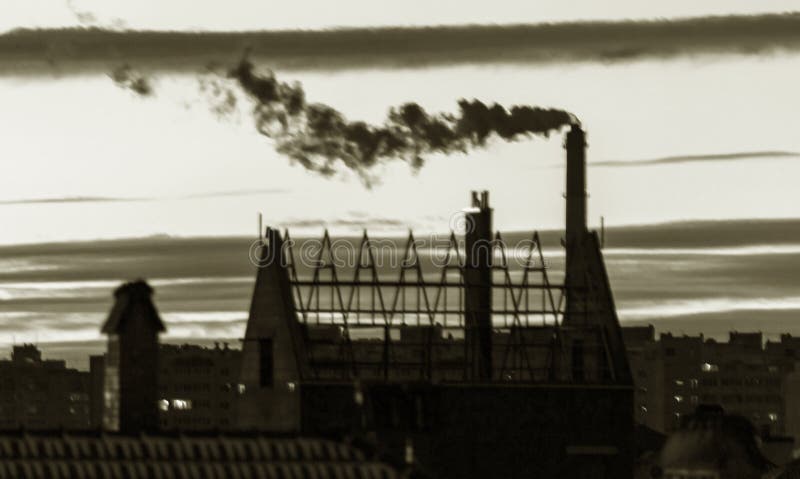Not a sharp abstract background. Not sharp blurred cityscape. City silhouette with a smoking industrial chimney against the sky at stock photos