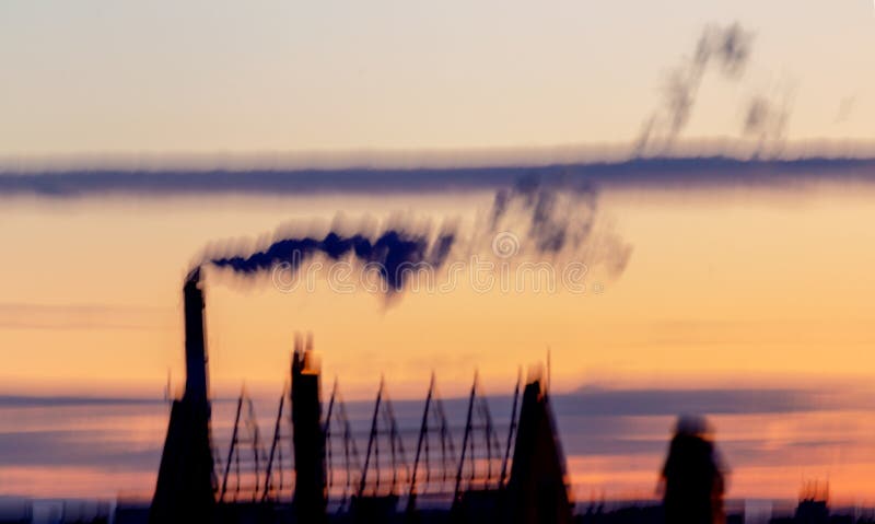 Not a sharp abstract background. Not sharp blurred cityscape. City silhouette with a smoking industrial chimney against the sky at royalty free stock photography