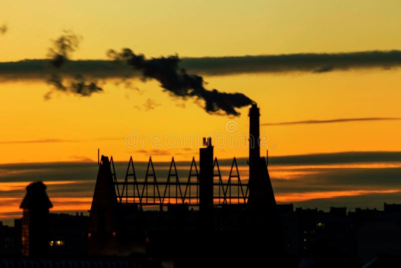 Not a sharp abstract background. Not sharp blurred cityscape. City silhouette with a smoking industrial chimney against the sky at royalty free stock photos