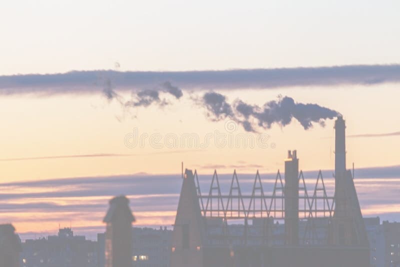 Not a sharp abstract background. Not sharp blurred cityscape. City silhouette with a smoking industrial chimney against the sky at royalty free stock photo
