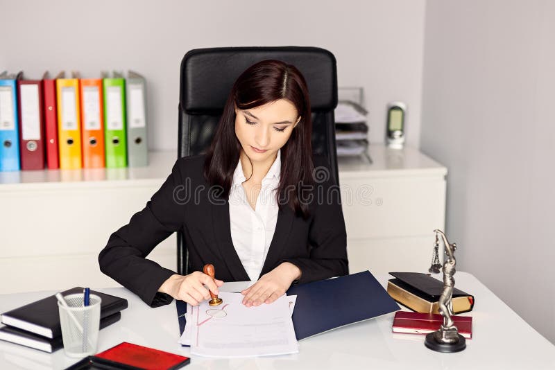 Notaio della donna che timbra il documento nel suo ufficio fotografie stock libere da diritti Notaio della donna che timbra il documento nel suo ufficio fotografie stock libere da diritti