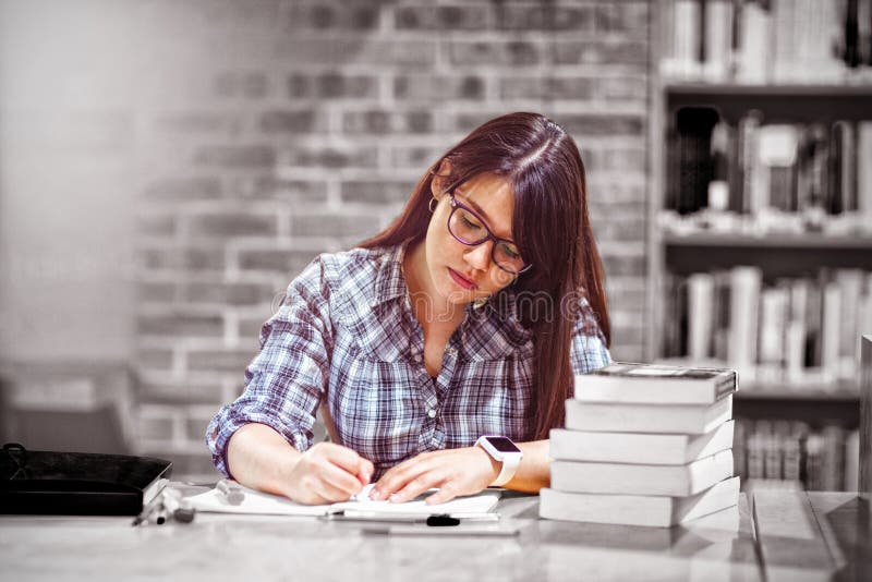 Notas da escrita do estudante fêmea na biblioteca imagens de stock Notas da escrita do estudante fêmea na biblioteca imagens de stock