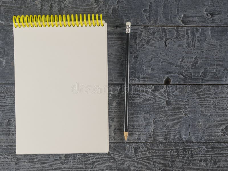 Note book and black pencil on a dark wooden table. The view from the top.