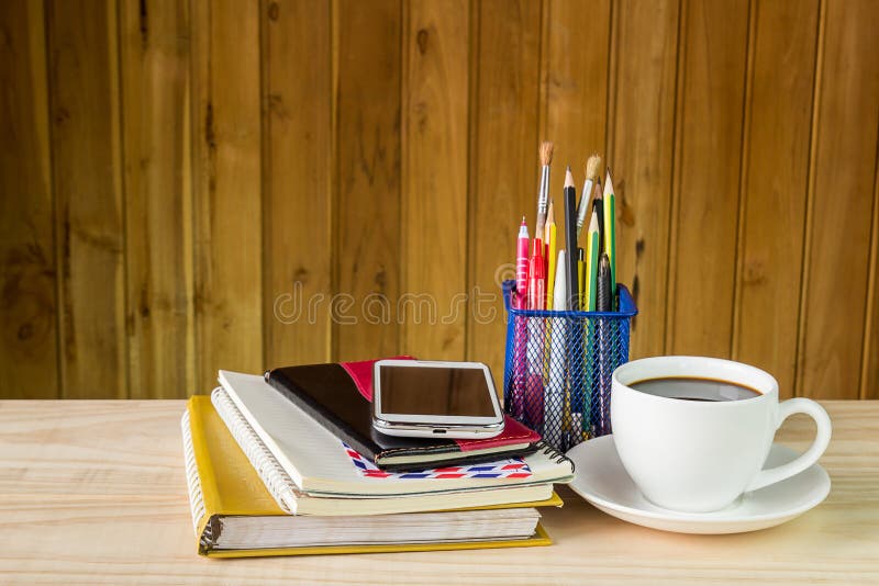 Note book,smart phone,coffee cup,and stack of book on wooden tab