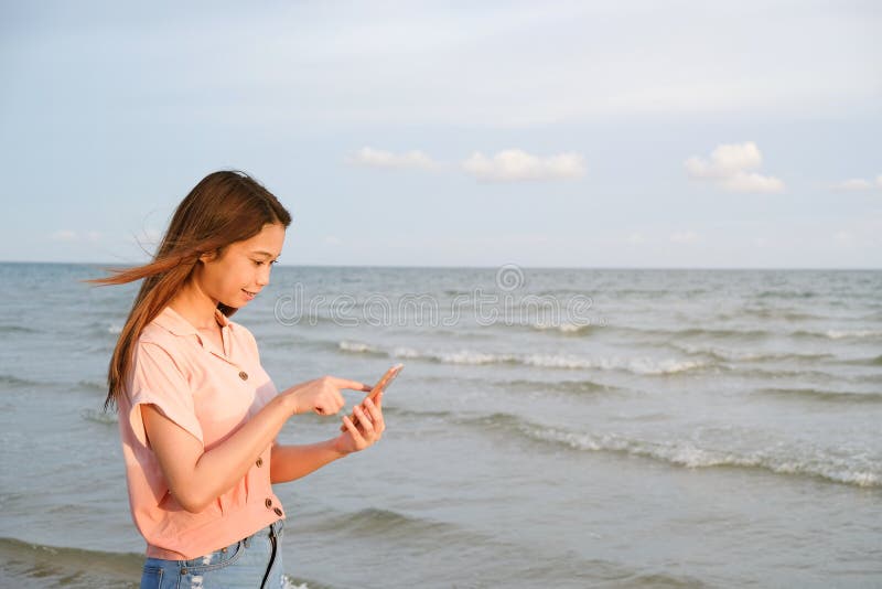 Note der jungen Frau am Handy, der am Strand, Sommerreisekonzept steht stockbild Note der jungen Frau am Handy, der am Strand, Sommerreisekonzept steht stockbild