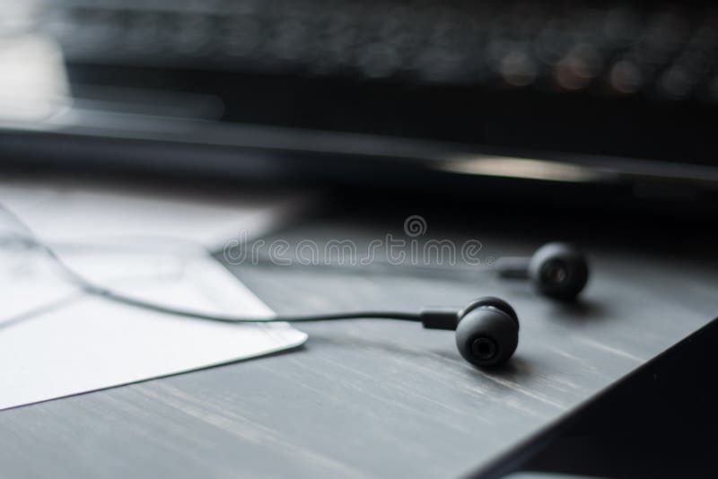 Notebook, glasses, earphone and smart phone on wood table top vie.