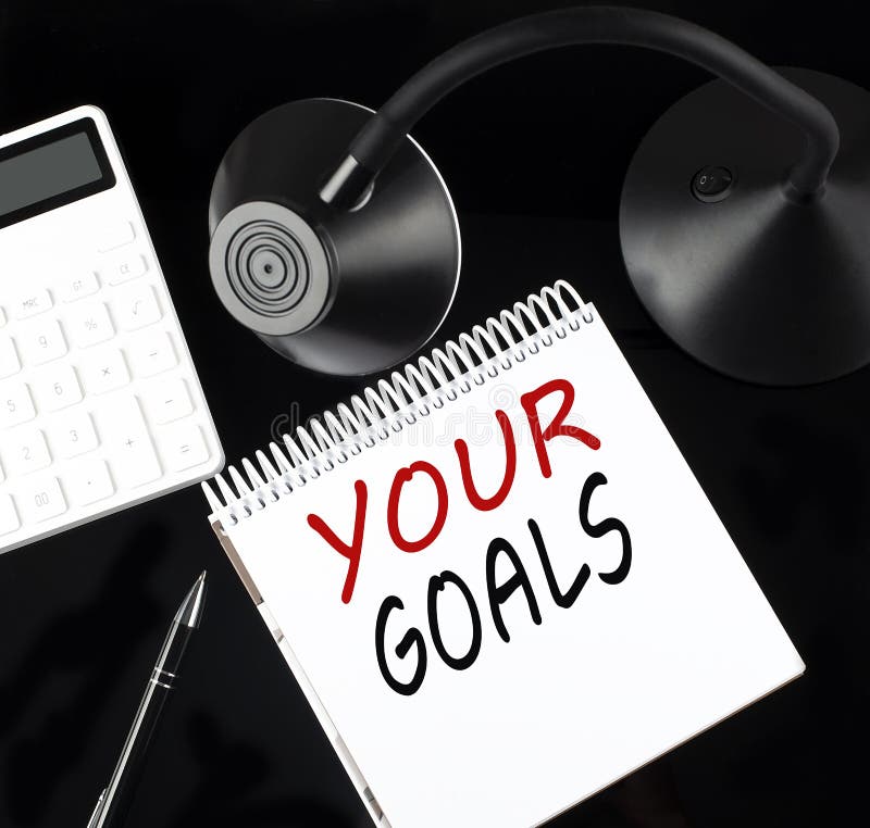 Notebook pe hârtie deschis cu text pentru obiectivele dvs. cu un calculator pentru stilou și o lampă pentru masă pe fundal negru royalty free stock photography