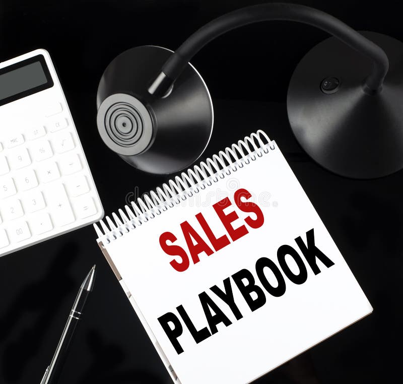 Notebook pe hârtie deschis cu un manual de revânzare text cu un calculator pentru stilou și o lampă pentru masă pe fond negru royalty free stock image
