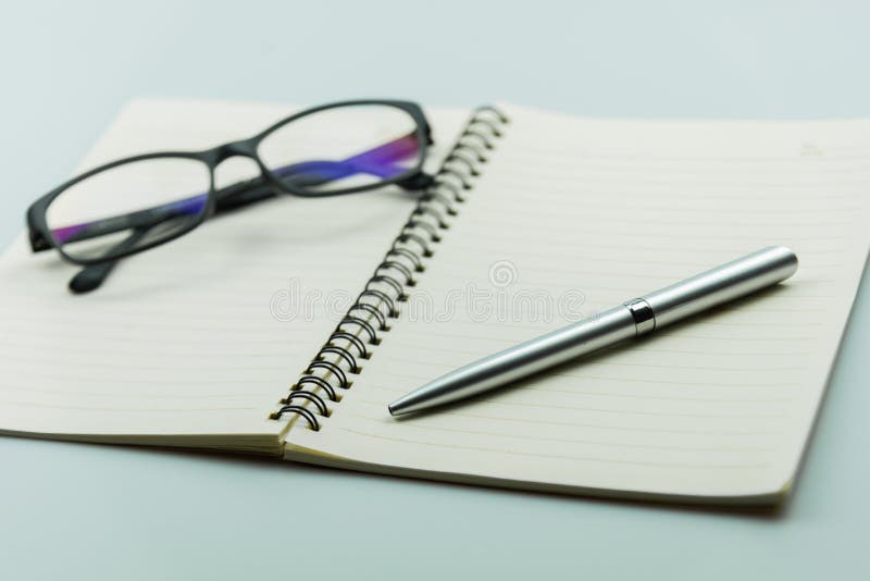 Notebook, pen and glasses on white background