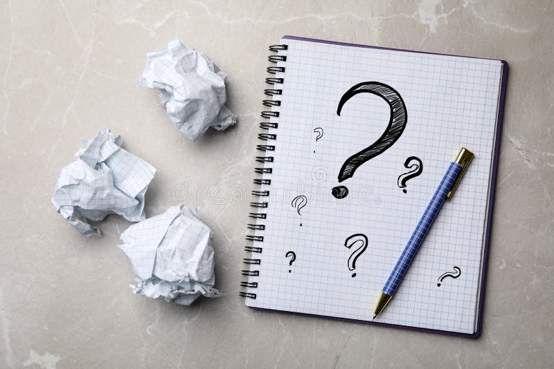 Notebook with Question Marks, Pen and Crumpled Paper Balls on Marble