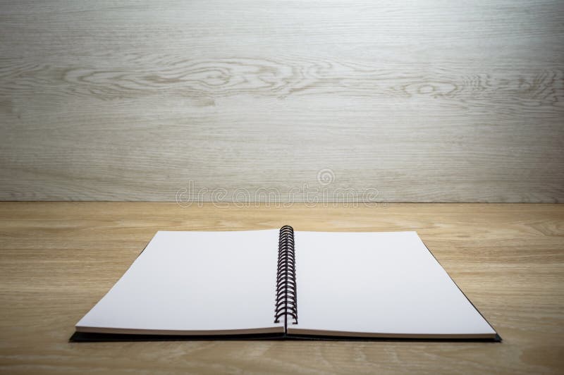 Notebook on wood table and wall. Empty page of notebook opened on wooden table with wooden wall
