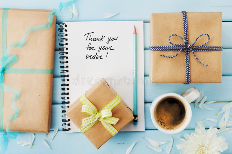 Notebook with the words Thank you for your order, pencil and gift or present box packed in kraft paper on blue wooden table royalty free stock photos Notebook with the words Thank you for your order, pencil and gift or present box packed in kraft paper on blue wooden table royalty free stock photos