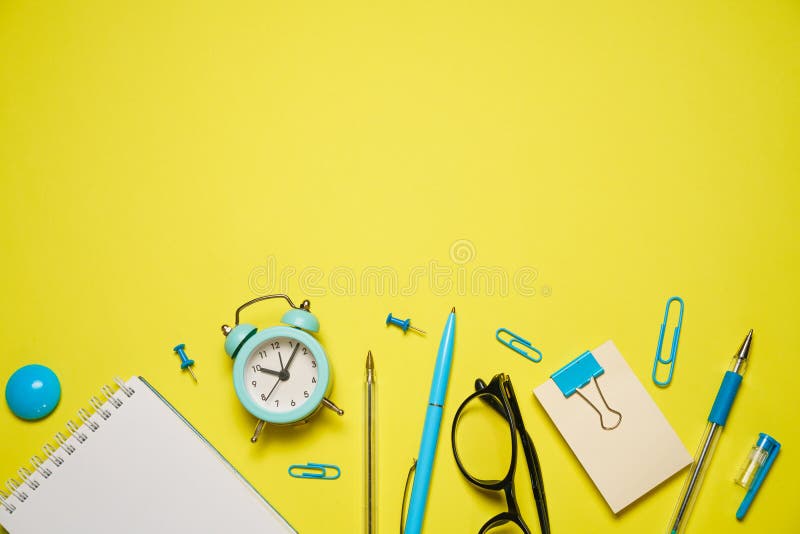 Notebook for writing pen and alarm clock with glasses on yellow background top royalty free stock image
