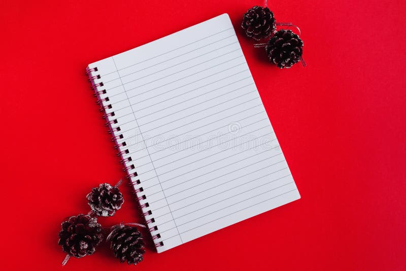 Notebook z pustymi stronami i ozdobnymi szyszkami sosnowymi w widoku u góry czerwonego tła