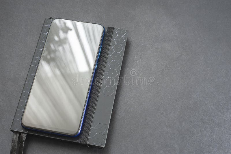 Notepad and Mobile Phone on a Black Background, Table. Financial