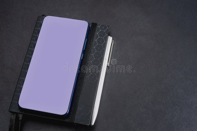 Notepad and Mobile Phone on a Black Background, Table. Financial