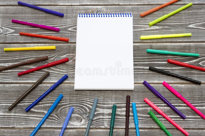 Notepad on a spring surrounded by colored markers. royalty free stock image