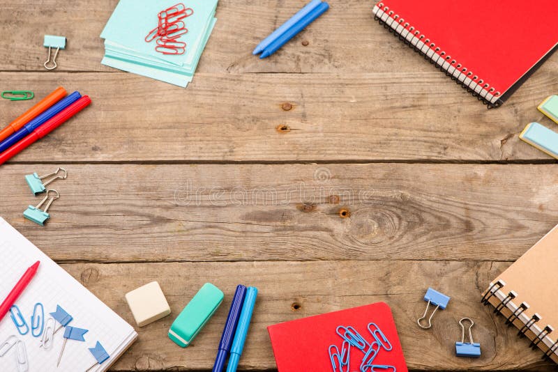 Notepads, papers, markers and other stationery on brown wooden table