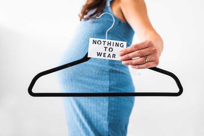 Nothing to Wear sign held by pregnant woman in the last month of pregnancy wearing stretchy blue dress showing her bump, maternity stock photo Nothing to Wear sign held by pregnant woman in the last month of pregnancy wearing stretchy blue dress showing her bump, maternity stock photo