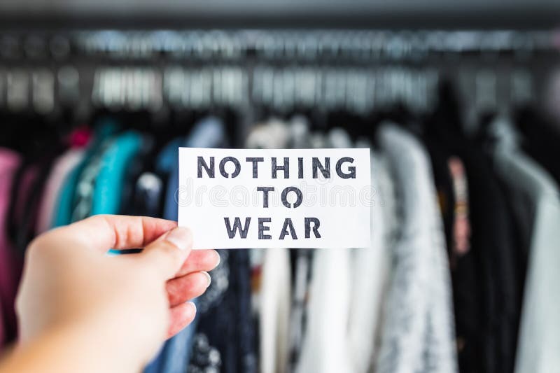 Shopping and consumerism, Nothing to Wear sign ironically held in front of wardrobe full of clothes stock photo Shopping and consumerism, Nothing to Wear sign ironically held in front of wardrobe full of clothes stock photo