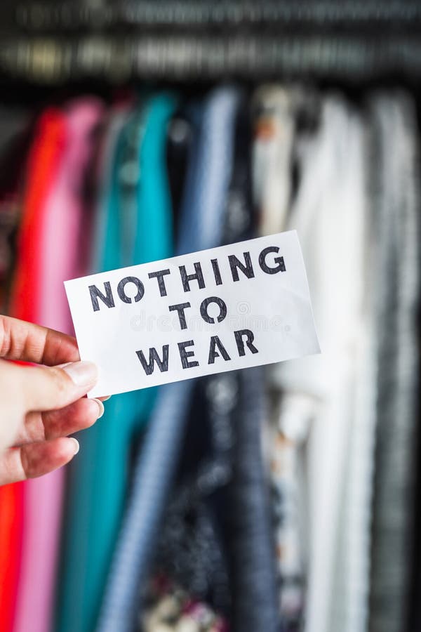 Shopping and consumerism, Nothing to Wear sign ironically held in front of wardrobe full of clothes stock photos Shopping and consumerism, Nothing to Wear sign ironically held in front of wardrobe full of clothes stock photos