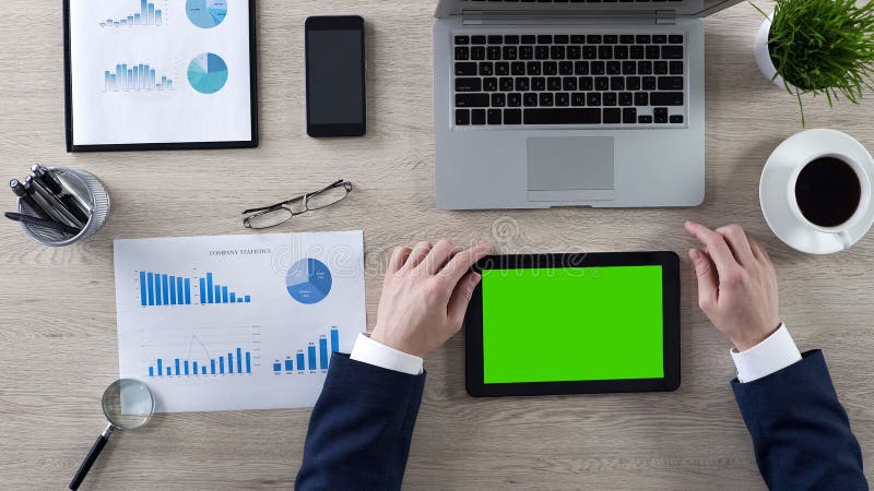 Noticias en la tableta con la pantalla verde, vista superior de la lectura del hombre de negocios del lugar de trabajo imágenes de archivo libres de regalías Noticias en la tableta con la pantalla verde, vista superior de la lectura del hombre de negocios del lugar de trabajo imágenes de archivo libres de regalías