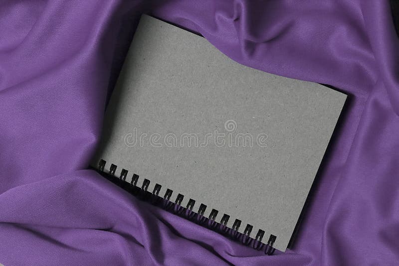 Notizbuch auf purpurrotem Gewebe, Notizbuch ist, Weinlesenotizbuchabdeckung grau lizenzfreie stockfotos