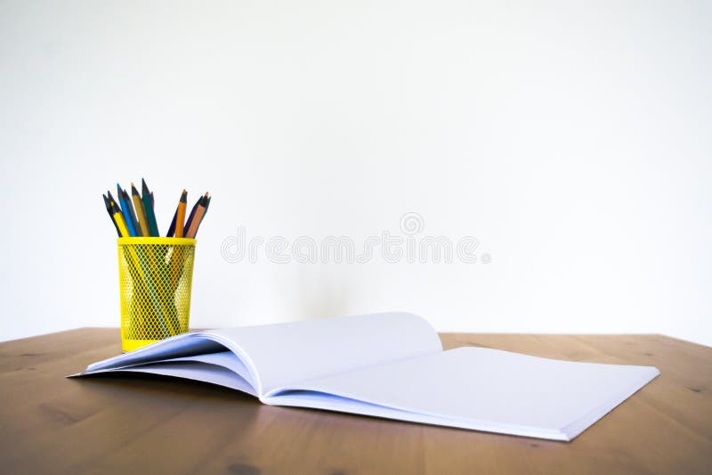 Notizbuch und Glas mit Bleistiften und Stiften auf einem Holztisch Front View lizenzfreies stockbild Notizbuch und Glas mit Bleistiften und Stiften auf einem Holztisch Front View lizenzfreies stockbild
