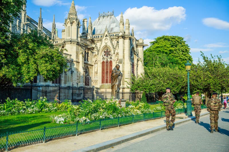 PARIS, FRANCE - JULY 1, 2017: Notre Dame of Paris side facade, with Armed Forces soldiers, keeping security of this high sensitive tourist landmark, after recent terrorist threat in Paris. PARIS, FRANCE - JULY 1, 2017: Notre Dame of Paris side facade, with Armed Forces soldiers, keeping security of this high sensitive tourist landmark, after recent terrorist threat in Paris.