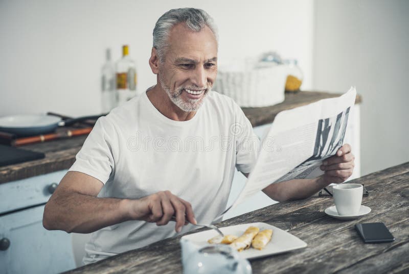 Notícia afirmada da leitura do homem durante o café da manhã imagens de stock Notícia afirmada da leitura do homem durante o café da manhã imagens de stock