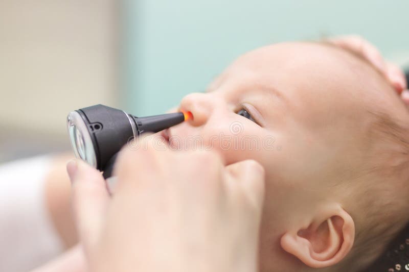 Nourrisson dans la clinique pédiatrique Main en gros plan du ` s de docteur avec le nez de examen du ` s de bébé d'otoscope moder photos stock Nourrisson dans la clinique pédiatrique Main en gros plan du ` s de docteur avec le nez de examen du ` s de bébé d'otoscope moder photos stock