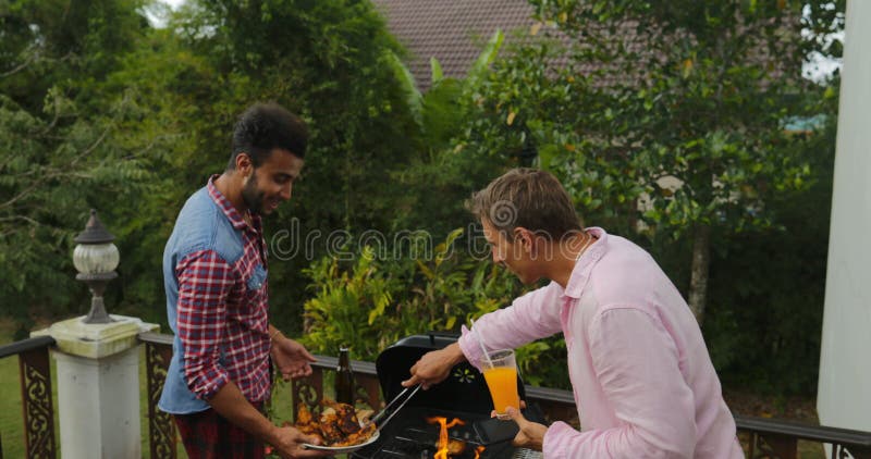 Nourriture de mise pour deux hommes sur le jeune groupe d'amis de barbecue se réunissant sur la terrasse d'été ayant la danse gai clips vidéos