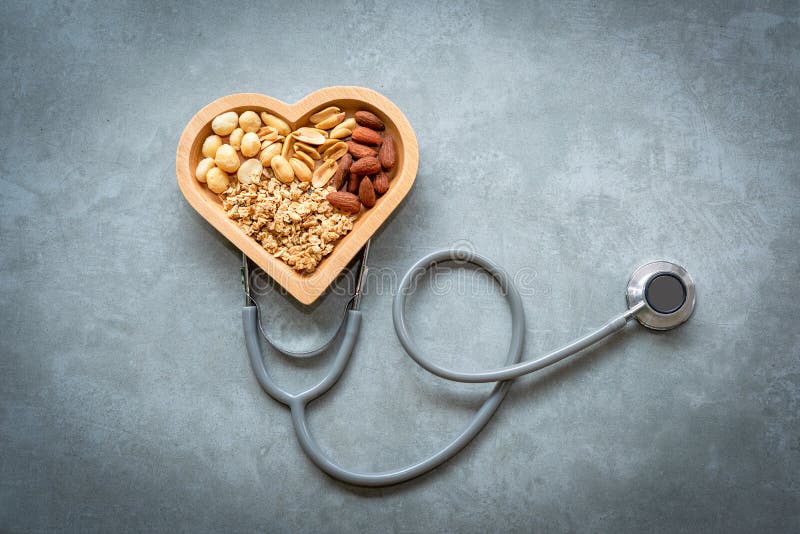 Nourritures saines Écrous mélangés dans la forme de coeur et stéthoscope avec des écrous pour le régime sur un fond concret Diffé photo stock Nourritures saines Écrous mélangés dans la forme de coeur et stéthoscope avec des écrous pour le régime sur un fond concret Diffé photo stock