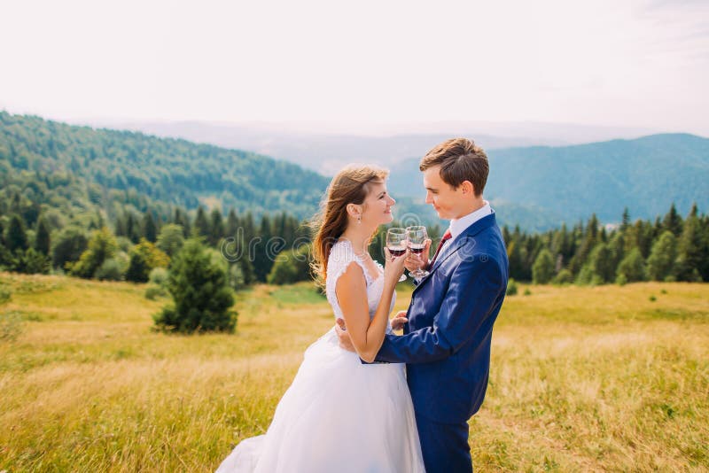 Nouveaux mariés gais buvant du vin dehors, célébrant leur mariage Forest Hills étonnant comme fond images libres de droits Nouveaux mariés gais buvant du vin dehors, célébrant leur mariage Forest Hills étonnant comme fond images libres de droits