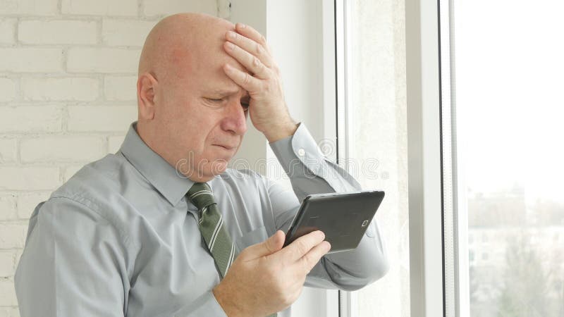 Nouvelles financières d'Image Reading Upset d'homme d'affaires sur la Tablette et le renversement de faire des gestes photographie stock libre de droits Nouvelles financières d'Image Reading Upset d'homme d'affaires sur la Tablette et le renversement de faire des gestes photographie stock libre de droits