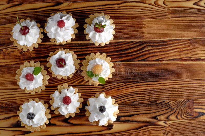 Nove dolci con le bacche della crema e di estate della proteina sulla tavola di legno fotografia stock Nove dolci con le bacche della crema e di estate della proteina sulla tavola di legno fotografia stock
