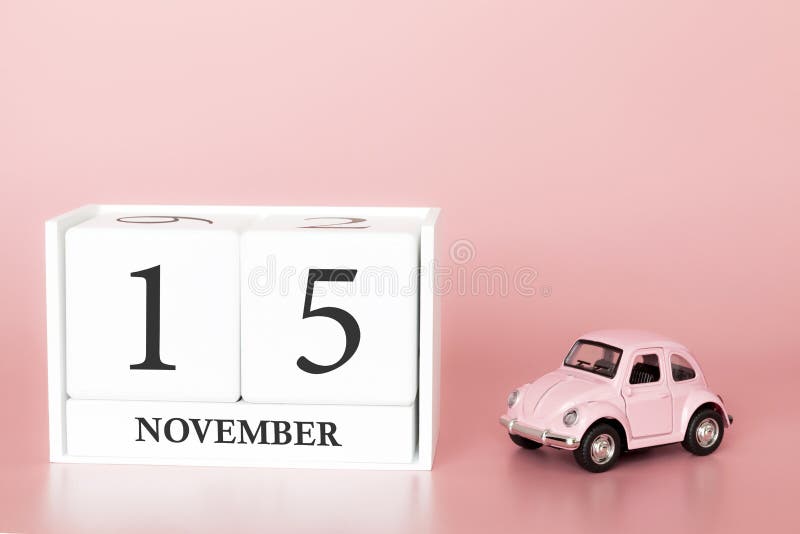 November 15th. Day 15 of month. Calendar cube on modern pink background with car