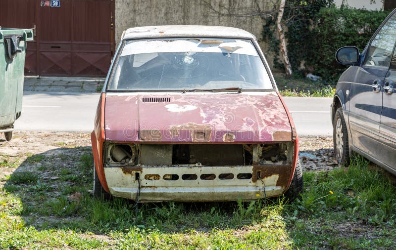 Old damaged and rusted Yugoslavian Zastava Yugo car with broken windscreen or windshield and peeled paint on the hood. stock photo Old damaged and rusted Yugoslavian Zastava Yugo car with broken windscreen or windshield and peeled paint on the hood. stock photo