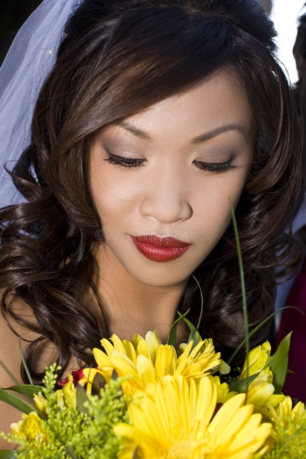 Beautiful ethnic bride looking at her bouquet. Beautiful ethnic bride looking at her bouquet