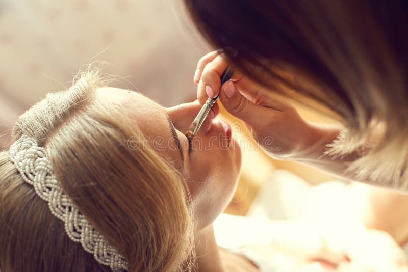 Novia hermosa joven que aplica maquillaje de la boda imagen de archivo libre de regalías Novia hermosa joven que aplica maquillaje de la boda imagen de archivo libre de regalías