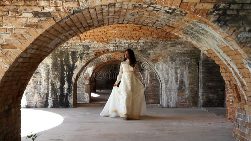 Novia que camina debajo de arcos del ladrillo