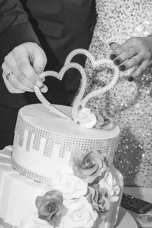 Novia y las manos y un pastel de bodas del novio con la decoración de la forma del hogar fotografía de archivo libre de regalías Novia y las manos y un pastel de bodas del novio con la decoración de la forma del hogar fotografía de archivo libre de regalías