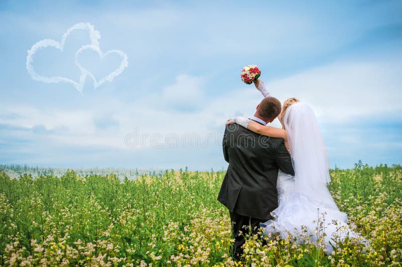 Novia y novio felices en un campo hermoso entre las flores foto de archivo Novia y novio felices en un campo hermoso entre las flores foto de archivo