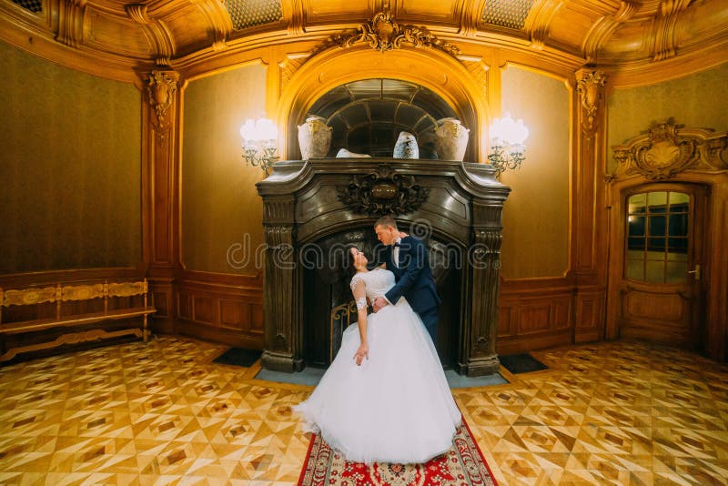 Novio elegante elegante que sumerge a su esposa encantadora, presentando en interior rico de la mansión clásica vieja imagenes de archivo Novio elegante elegante que sumerge a su esposa encantadora, presentando en interior rico de la mansión clásica vieja imagenes de archivo