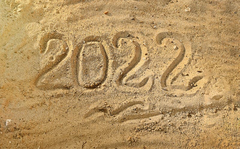 Novo ano 2022 escrito à mão sobre areia úmida na praia por mar ou oceano. contagem regressiva na véspera do feriado imagem de stock royalty free